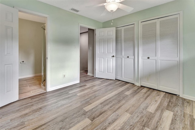 unfurnished bedroom featuring baseboards, light wood finished floors, visible vents, and multiple closets