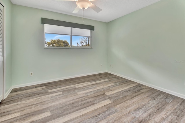 unfurnished room with ceiling fan, a textured ceiling, wood finished floors, and baseboards