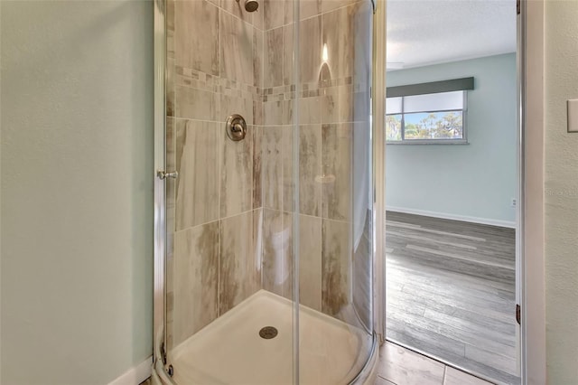 full bathroom with a shower stall, baseboards, and wood finished floors