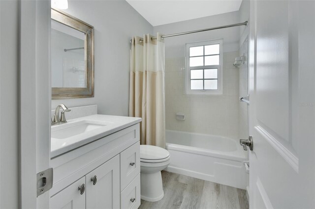 full bathroom with shower / bathtub combination with curtain, toilet, hardwood / wood-style flooring, and vanity