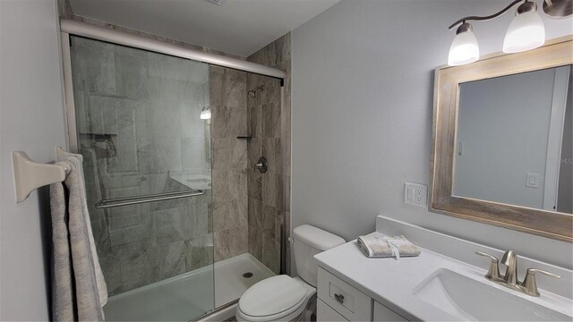 bathroom featuring vanity, toilet, and a shower with shower door