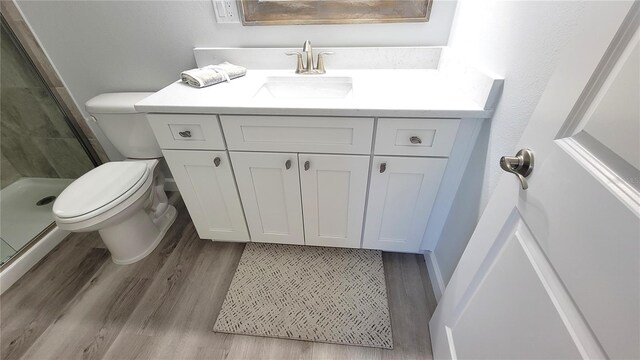 bathroom with vanity, toilet, hardwood / wood-style floors, and an enclosed shower