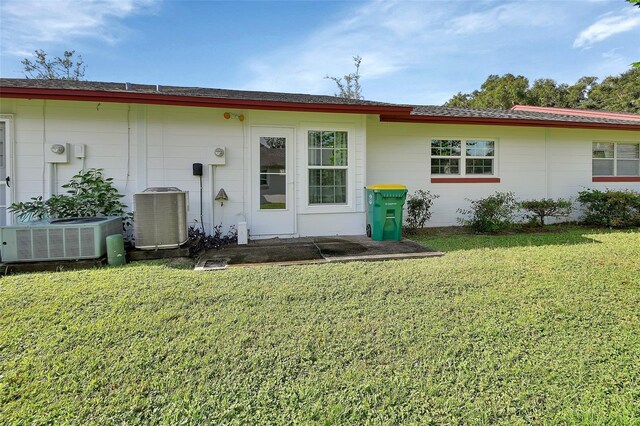 rear view of house with a yard and central air condition unit