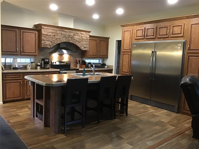 kitchen featuring an island with sink, sink, a breakfast bar area, stainless steel appliances, and dark wood-type flooring