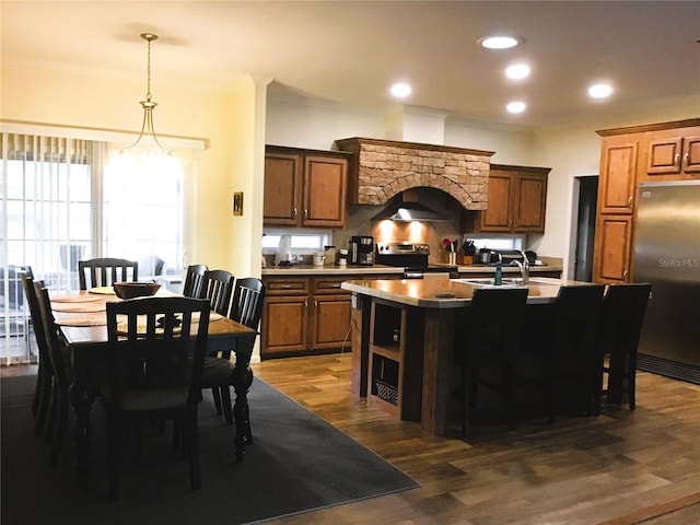 kitchen featuring pendant lighting, a center island with sink, stainless steel electric range, fridge, and dark hardwood / wood-style floors