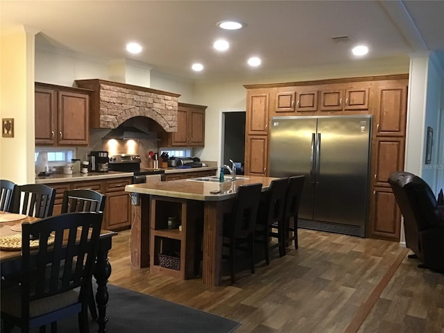 kitchen with a center island with sink, a breakfast bar area, appliances with stainless steel finishes, dark hardwood / wood-style floors, and sink