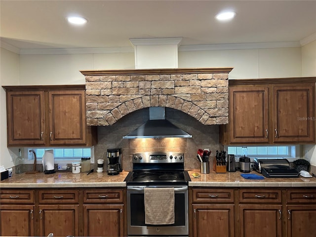 kitchen with backsplash, wall chimney exhaust hood, crown molding, and stainless steel electric range