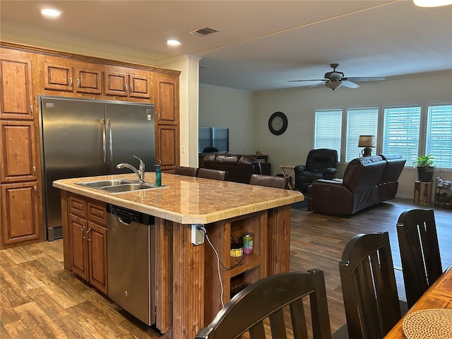 kitchen with stainless steel appliances, ceiling fan, a center island with sink, dark hardwood / wood-style flooring, and sink