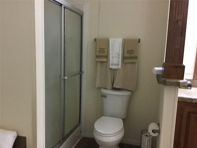 bathroom with toilet, vanity, and a shower with door