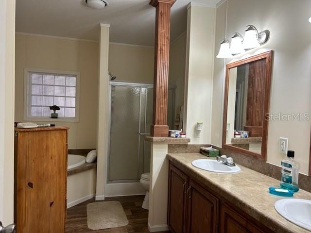 full bathroom featuring toilet, double vanity, wood-type flooring, independent shower and bath, and ornate columns