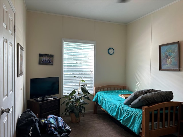 bedroom with ornamental molding and dark colored carpet