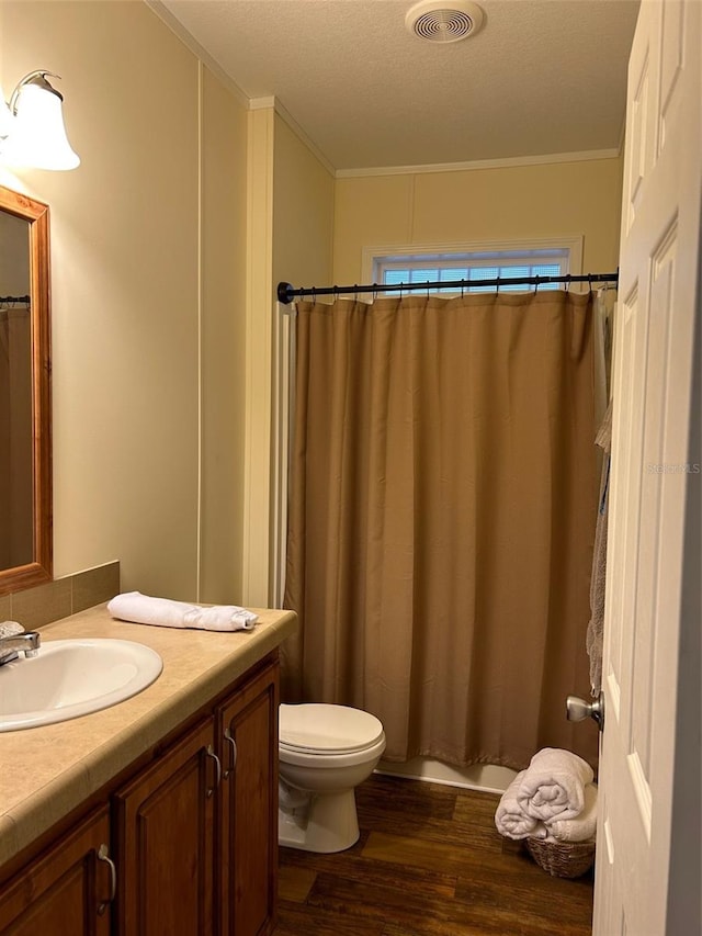 bathroom featuring vanity, hardwood / wood-style floors, a textured ceiling, toilet, and ornamental molding