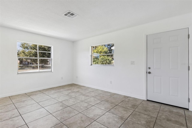 spare room featuring light tile patterned floors and a wealth of natural light