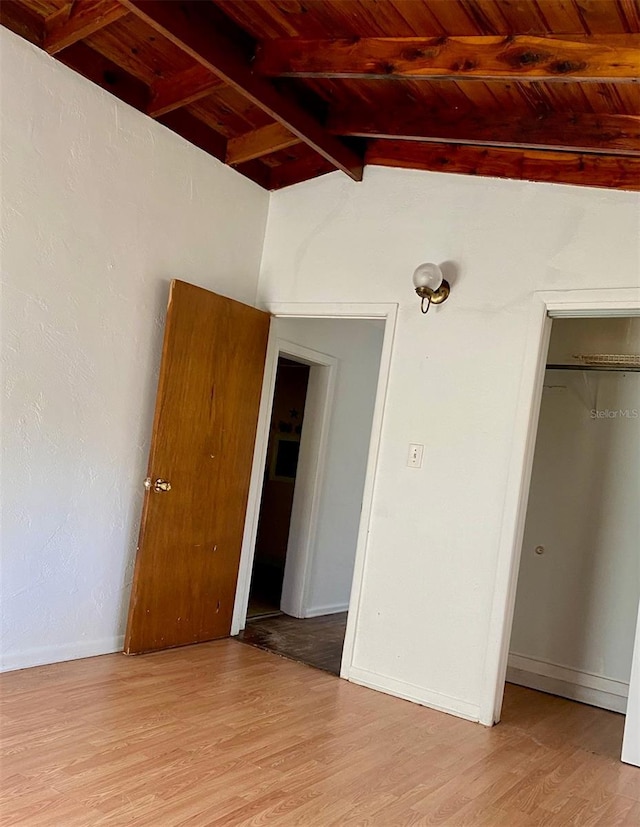 unfurnished bedroom with wood ceiling, a closet, lofted ceiling with beams, and light hardwood / wood-style floors