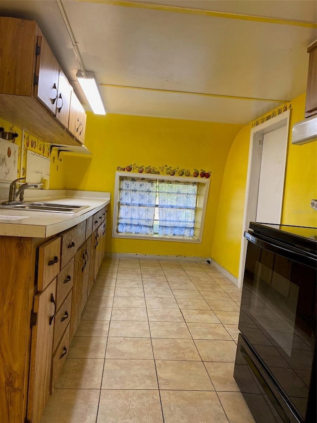 kitchen with light tile patterned floors, black stove, and sink