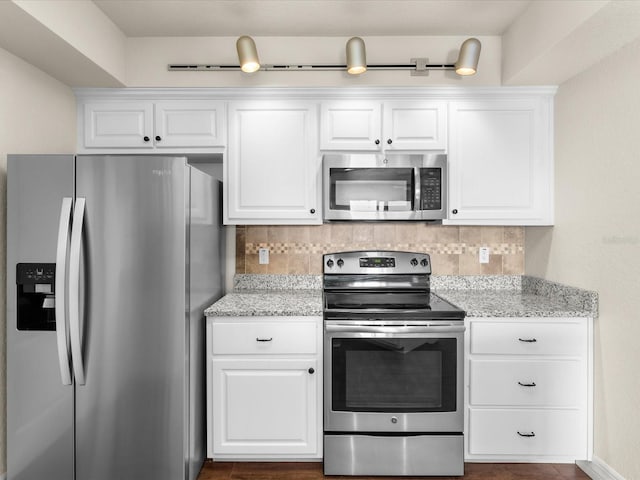 kitchen featuring light stone countertops, white cabinetry, tasteful backsplash, and stainless steel appliances