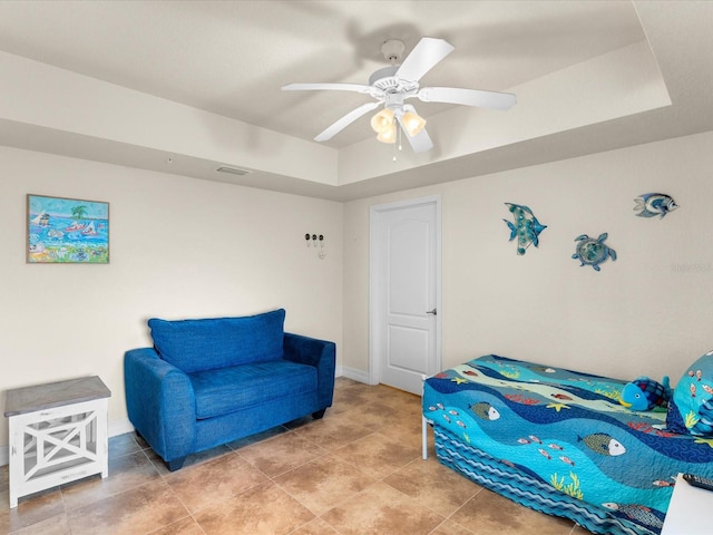 bedroom featuring light tile floors, ceiling fan, and a tray ceiling