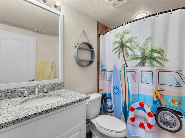 bathroom with a textured ceiling, large vanity, and toilet