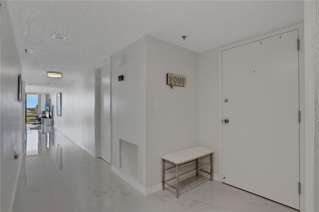 hallway with light tile floors and a textured ceiling