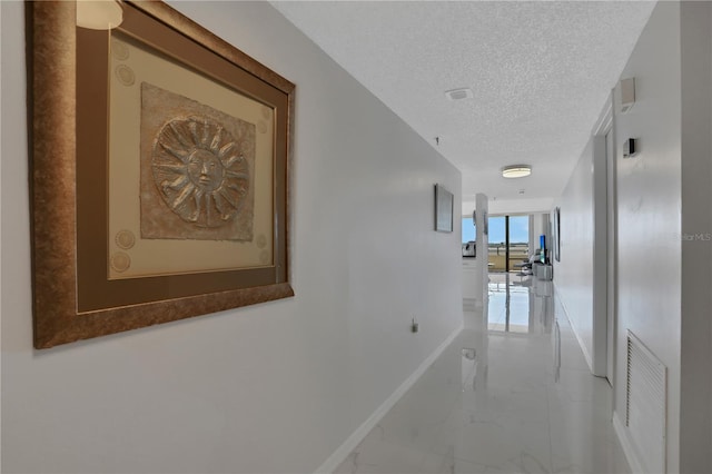 hallway with light tile floors and a textured ceiling