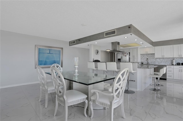 dining area with light tile floors, a textured ceiling, and sink