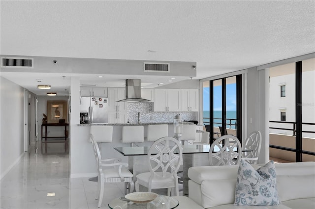 living room with sink, light tile floors, floor to ceiling windows, a water view, and a textured ceiling