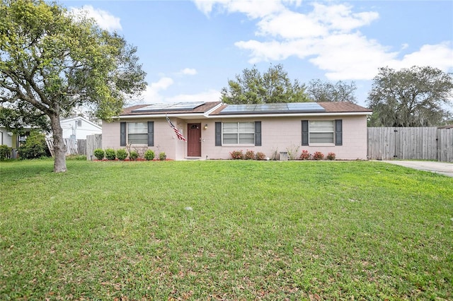 ranch-style home with a front yard and solar panels