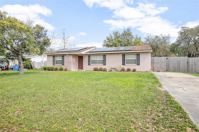 ranch-style house with solar panels and a front lawn