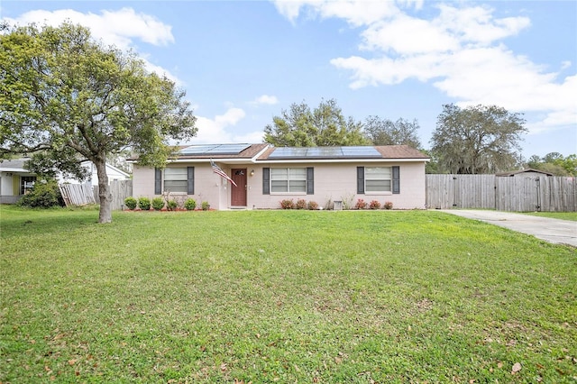 ranch-style house featuring a front lawn and solar panels