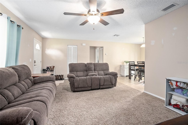 carpeted living room with a textured ceiling and ceiling fan