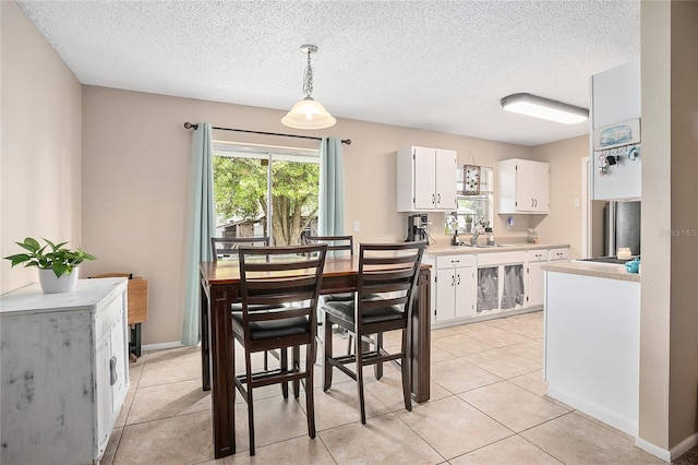 dining area with light tile floors, a textured ceiling, and sink