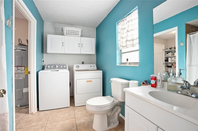 bathroom with toilet, vanity, washing machine and clothes dryer, electric water heater, and tile flooring