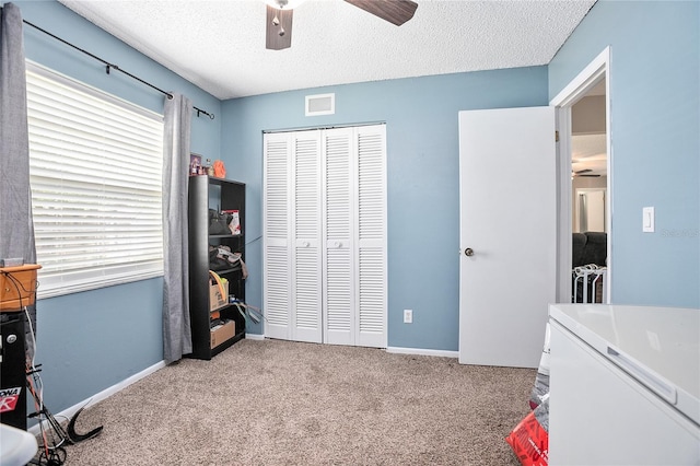 carpeted bedroom with a textured ceiling, a closet, ceiling fan, and multiple windows