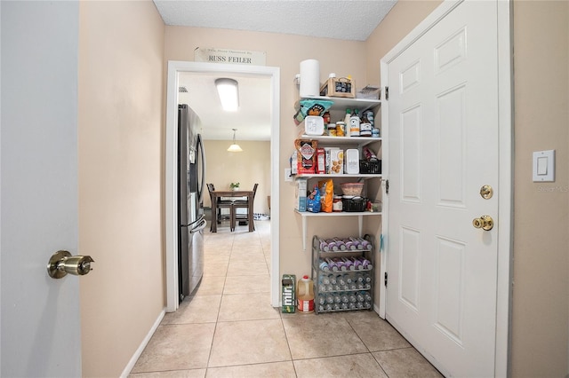 corridor featuring a textured ceiling and light tile floors