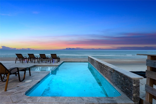 pool at dusk featuring a water view