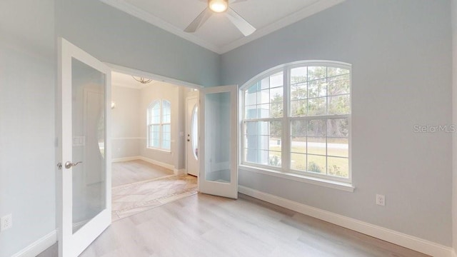 empty room featuring french doors, plenty of natural light, and crown molding