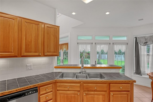 kitchen featuring light tile patterned flooring, tasteful backsplash, sink, stainless steel dishwasher, and tile counters