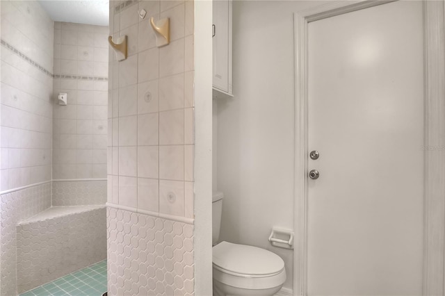 bathroom featuring a tile shower and toilet