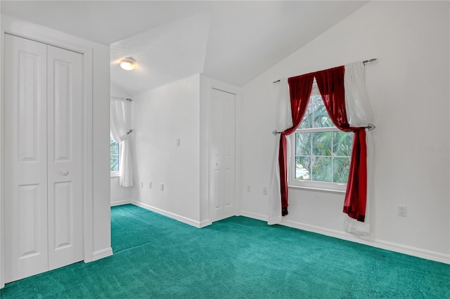 interior space with vaulted ceiling, multiple closets, and carpet flooring