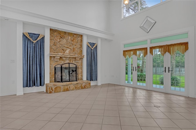 unfurnished living room featuring plenty of natural light, a fireplace, a high ceiling, and light tile patterned floors