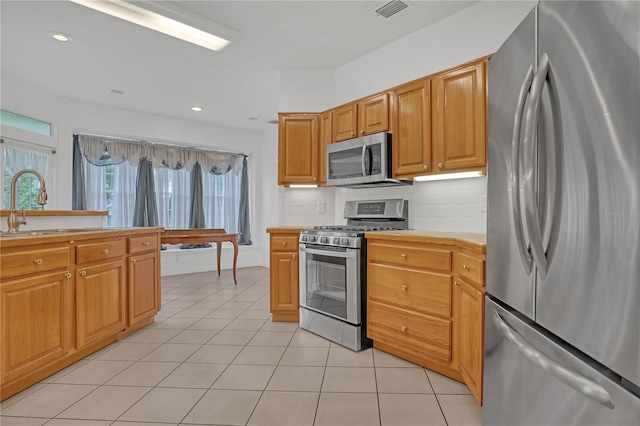 kitchen featuring backsplash, light tile patterned floors, stainless steel appliances, and sink