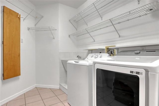 clothes washing area featuring light tile patterned floors and washing machine and clothes dryer