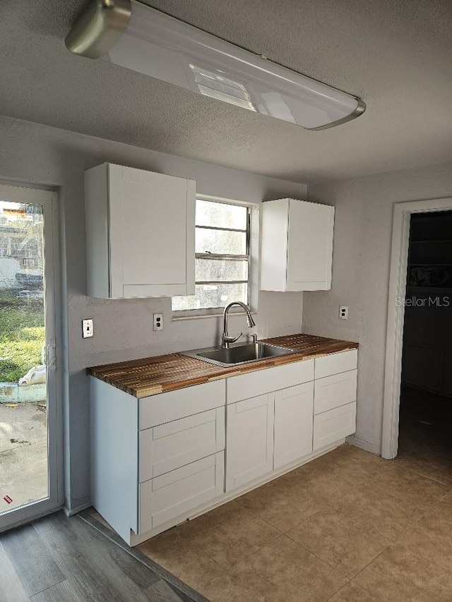 kitchen with light tile floors, white cabinetry, and sink