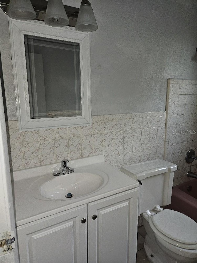 full bathroom with toilet, large vanity, shower / bath combination, tile walls, and backsplash