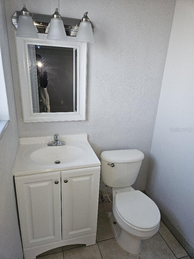 bathroom with toilet, vanity, and tile flooring