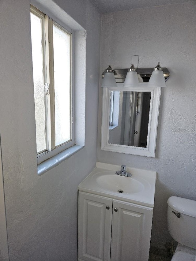 bathroom featuring toilet, a wealth of natural light, and vanity