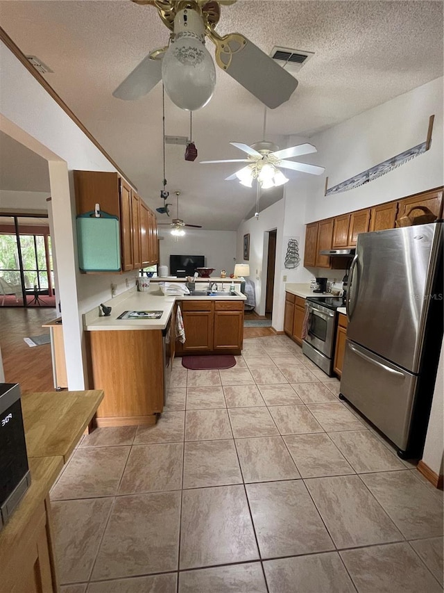 kitchen with light tile patterned flooring, lofted ceiling, ceiling fan, kitchen peninsula, and stainless steel appliances