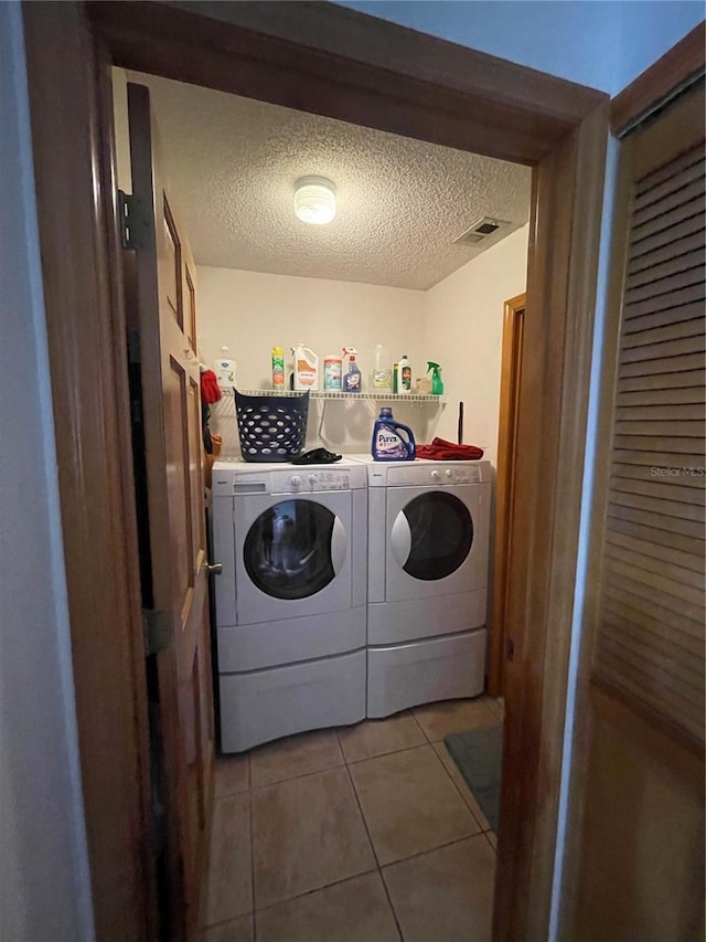 clothes washing area featuring light tile patterned flooring, a textured ceiling, and independent washer and dryer