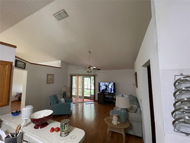 living room featuring ceiling fan, dark wood-type flooring, vaulted ceiling, and a textured ceiling