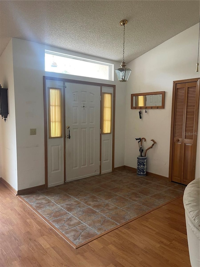 entrance foyer featuring hardwood / wood-style floors, vaulted ceiling, and a textured ceiling